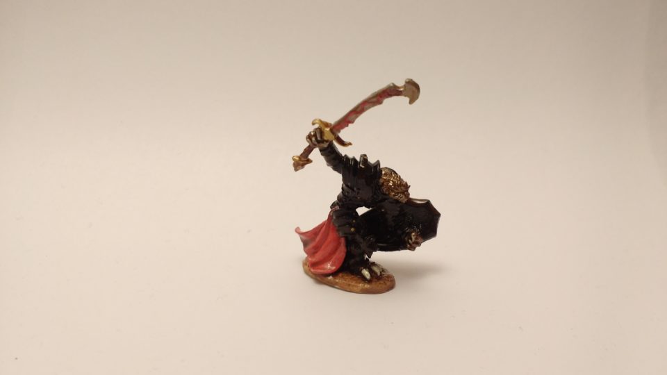 Dragonman Warrior miniature from Reaper Bones with golden scales, black armor, and red highlights.