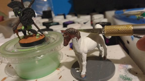 An inexpensive toy horse with an exacto knife poised to cut off it's head.